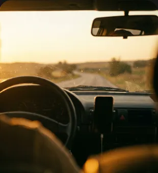A phone playing on the dashboard of a car at sunrise